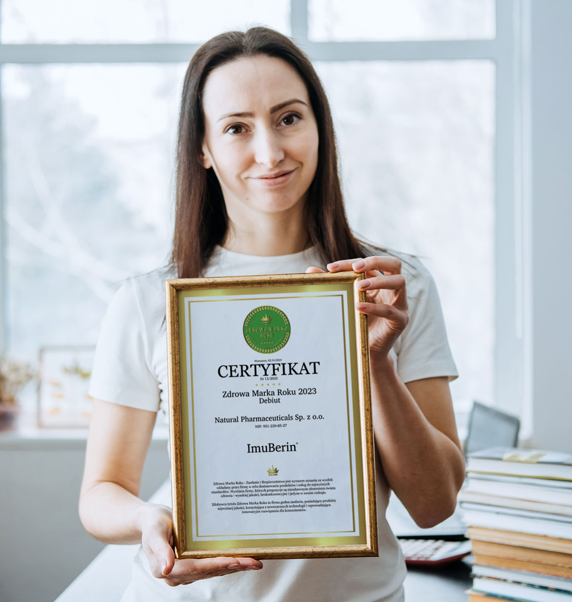 Natural Pharmaceuticals Imuberin® Mosolygós nő, aki keretben tartja az Imuberin®® étrend-kiegészítőnek járó 2023-as Év Egészséges Márka díját.